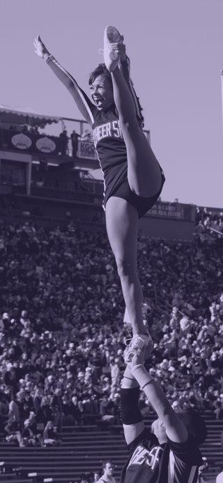 A cheerleader held aloft in a heel-stretch stunt above a crowd.